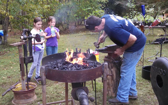 Brad Greenwood demonstrating how to use a forge at a craft show.